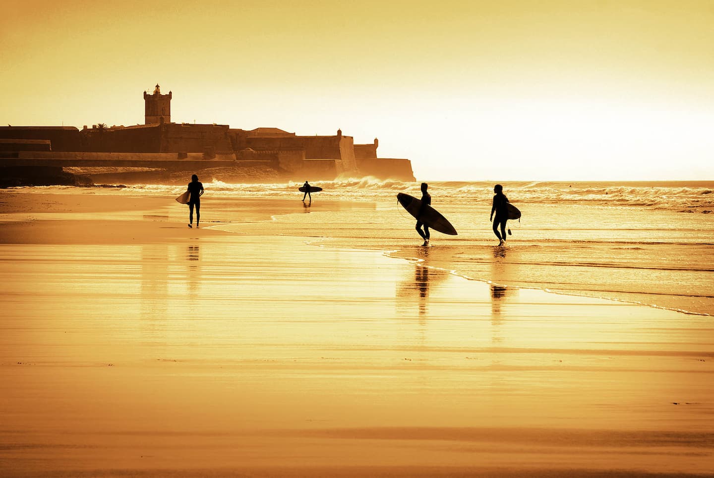 Surfers at Carcavelos beach in golden evening light