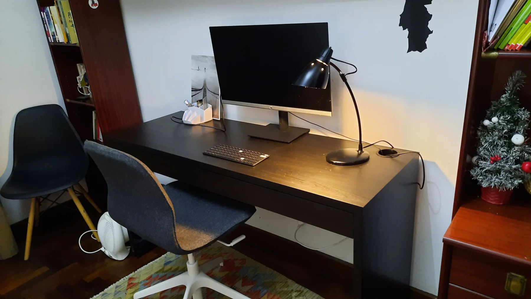 Dedicated desk with a large computer monitor, keyboard and two chairs
